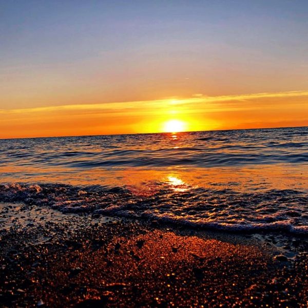 Sonnenuntergang am Meer mit Wellen und Strand.