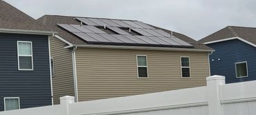 Solar panels installed on a residential rooftop behind a white fence.