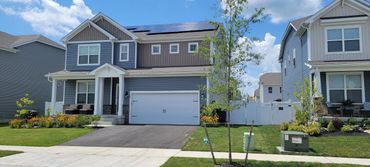 Modern suburban house with solar panels and a well-kept garden under a clear sky.