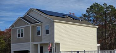 A two-story house with solar panels on the roof and an American flag at the entrance.