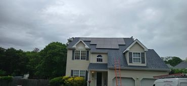A house with solar panels on the roof under a cloudy sky.