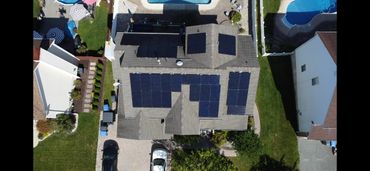 Aerial view of a house with multiple solar panels installed on the roof.