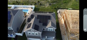 Aerial view of a house with solar panels, a pool, and a neighboring house under construction.