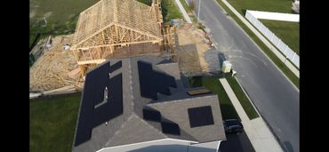 Aerial view of a house with solar panels and a wooden house under construction nearby.