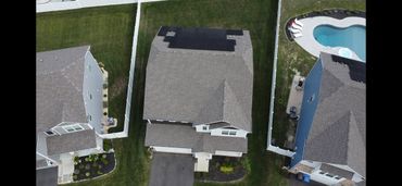 Aerial view of suburban houses with solar panels and a swimming pool.