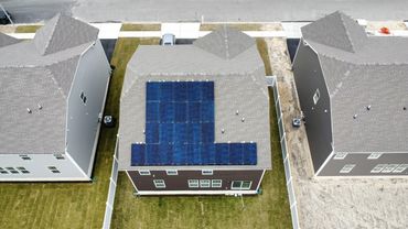 Aerial view of suburban houses with solar panels on one roof.