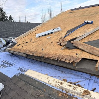 Roof under renovation with old plywood exposed and tools scattered.