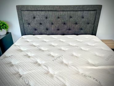 Modern bed with grey upholstered headboard and white mattress.