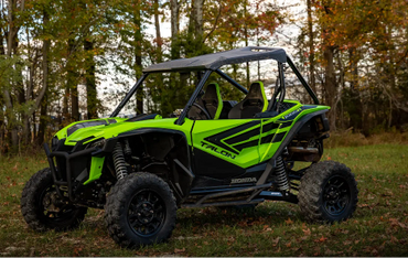 Bright green Honda Talon off-road vehicle parked on grass near autumn trees.