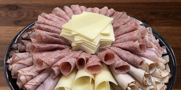 A platter of assorted sliced deli meats and cheeses arranged in a circular pattern.
