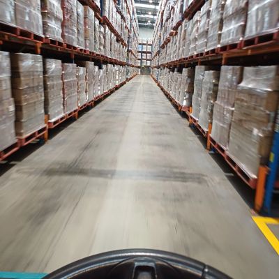 Warehouse aisle with shelves full of pallets.
