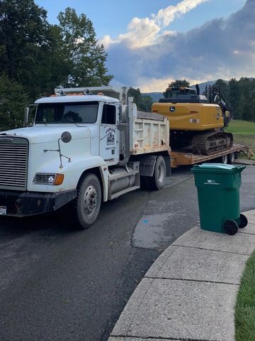 frieghtliner dump truck hauling john deere excavator 