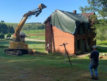 john deere excavator demolishing brick farm house    
