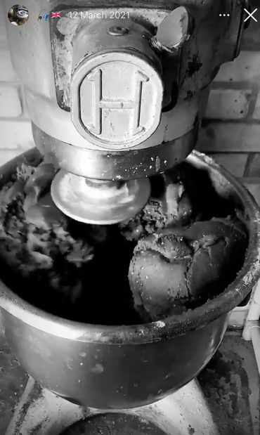Vintage dough mixer kneading dough in a metal bowl.