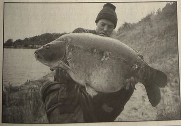 Man holding a large fish near the water's edge.