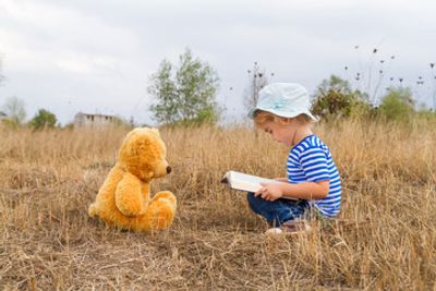 Young child enjoying reading to stuffed bear.