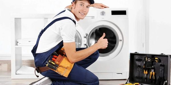 Technician giving thumbs up in front of washing machine.