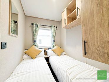 Two single beds in a compact bedroom with wooden cabinets.