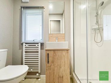 Bright modern bathroom with wooden vanity and glass shower.