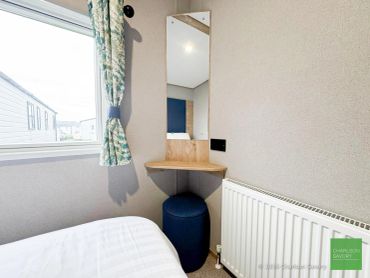 Small corner vanity with mirror and stool in a bedroom.