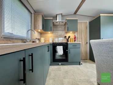 Modern kitchen with teal cabinets and wooden accents.