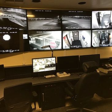 Security room with multiple surveillance monitors showing various locations.