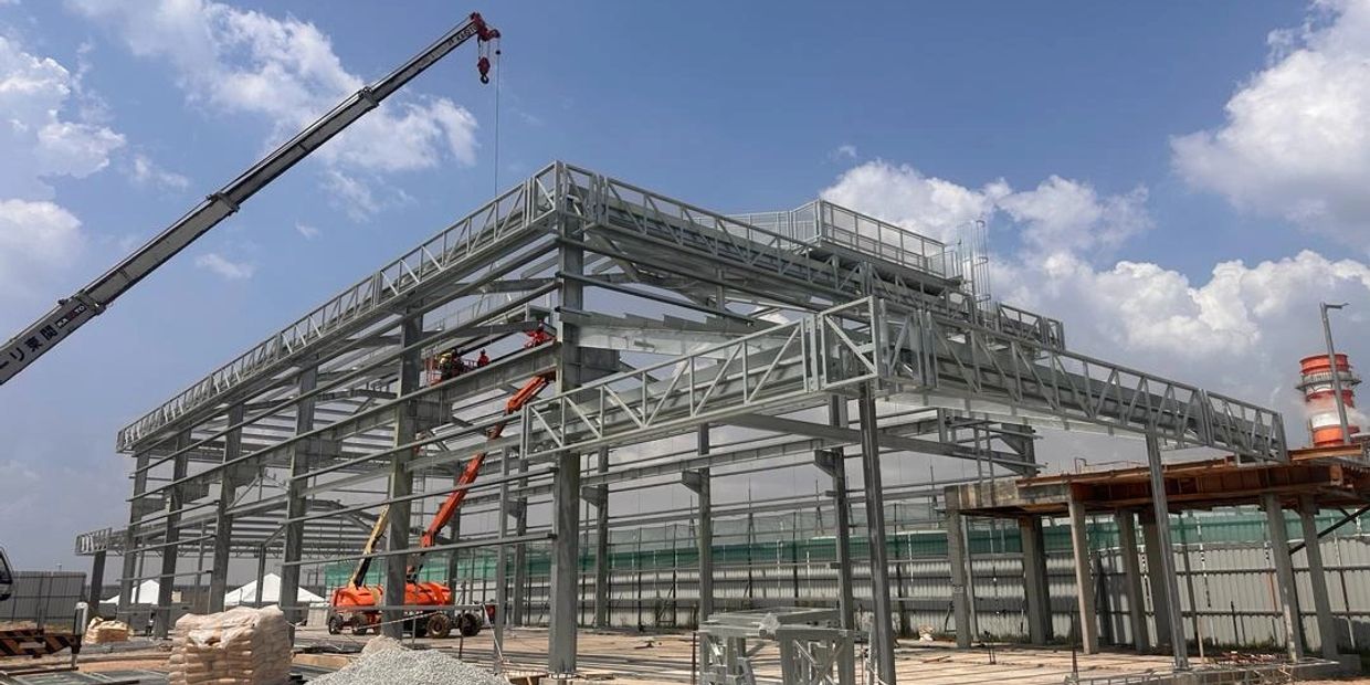 Steel framework of a building under construction with cranes and machinery.