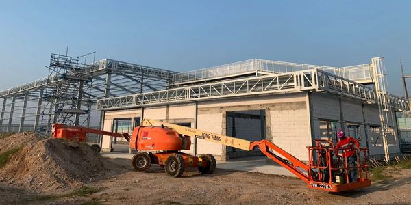 Construction site with machinery and scaffolding under a clear blue sky.