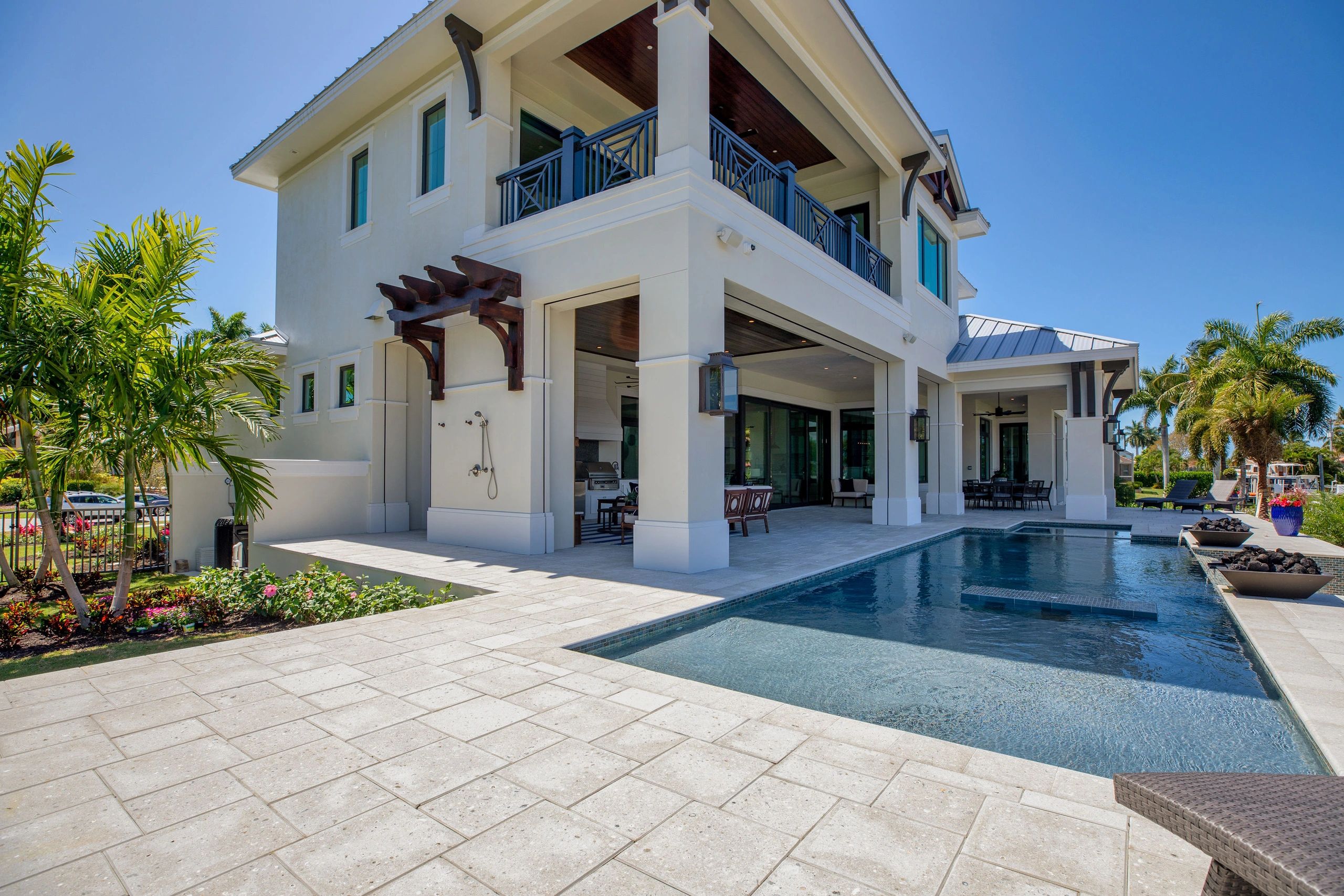 Modern two-story house with a pool and outdoor seating area under clear blue sky.