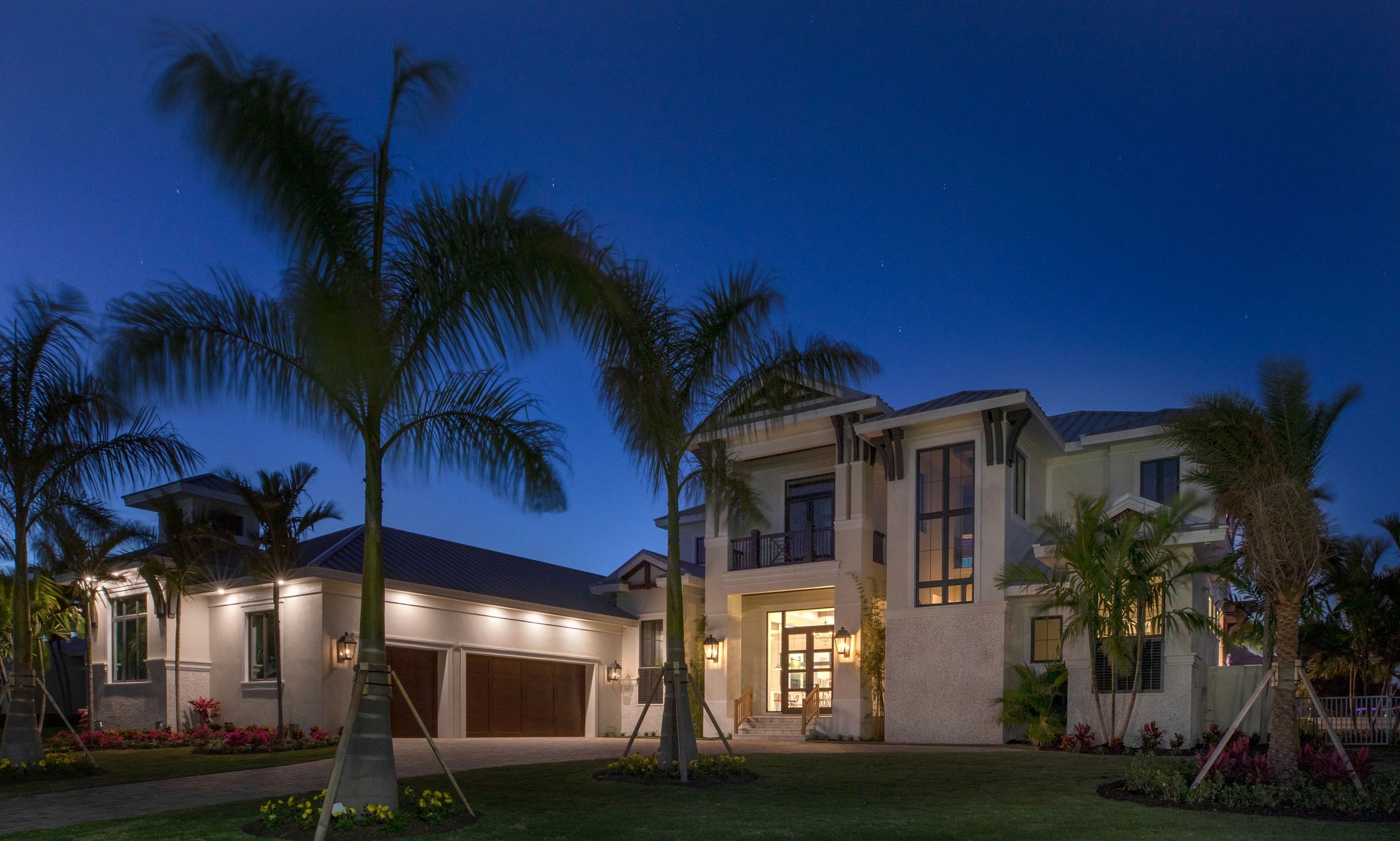 Modern house with palm trees at dusk under a clear sky.