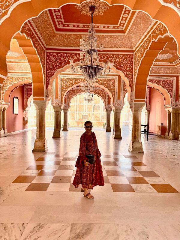 Woman in traditional attire inside an ornately decorated palace hall.