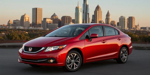 Red Honda sedan parked with a city skyline in the background.