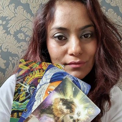 a smiling woman holding tarot cards.