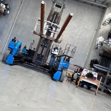 A large blue forklift inside a spacious warehouse with concrete floors.