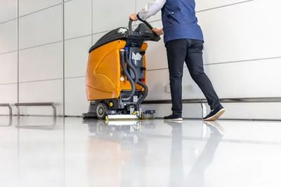 cleaner using auto scrubber machine to clean commercial white floors