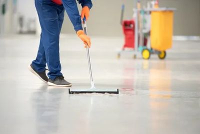 cleaner sweeping commercial floor wearing blue uniform