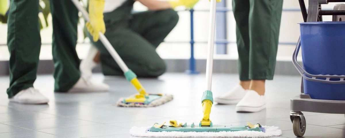 three cleaners sweeping tiles floors with dust mop