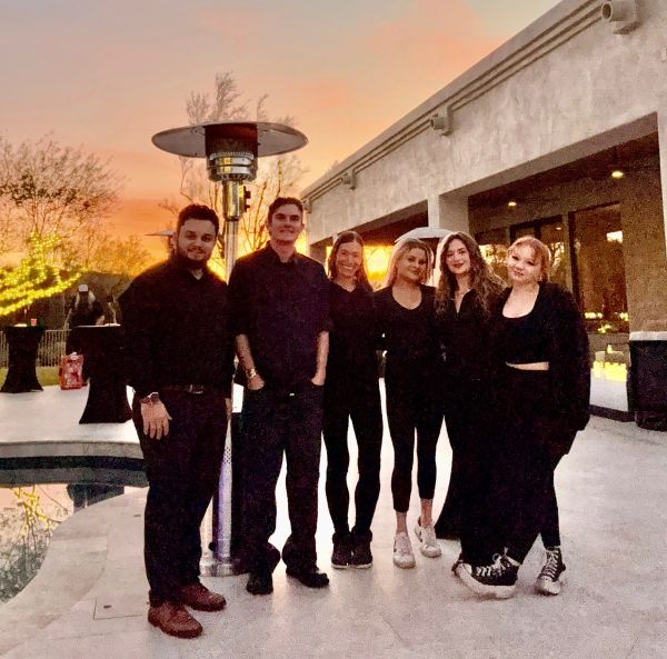 Group of six friends posing at sunset by a pool.