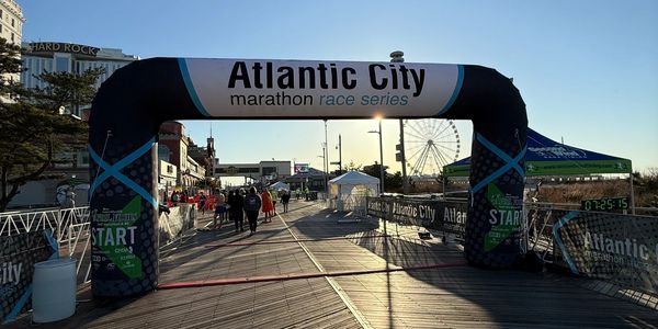 Start line of Atlantic City marathon race series on a boardwalk at sunrise.