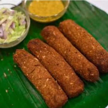 Four deep-fried kebabs on a banana leaf with dipping sauces.