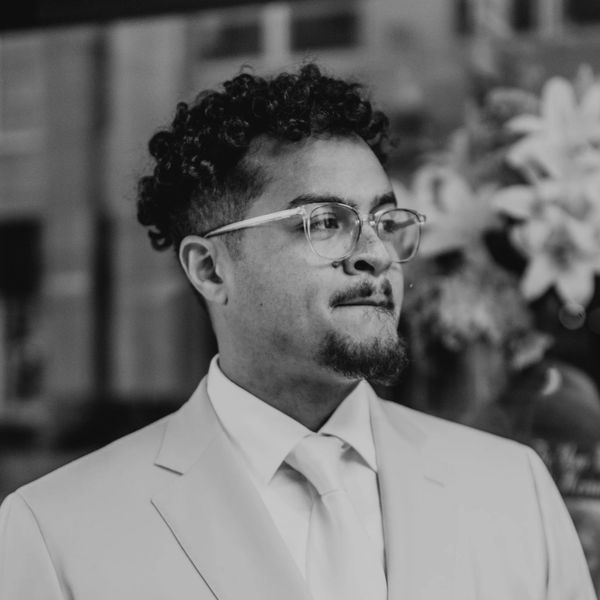 Man in suit and glasses looking away thoughtfully.