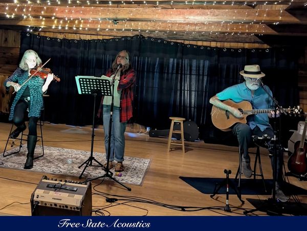 Three musicians perform on a small stage with string and wind instruments.