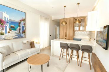 Bright modern living room with a white sofa, wooden accents, and a coastal painting.