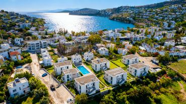 Aerial view of a coastal town with white houses and a swimming pool.