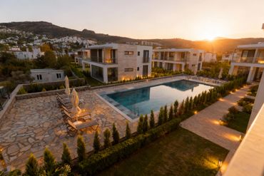 Modern villas surrounding a lit swimming pool at sunset.