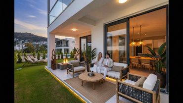 Couple enjoying an elegant outdoor patio with modern furniture and fire pit at sunset.