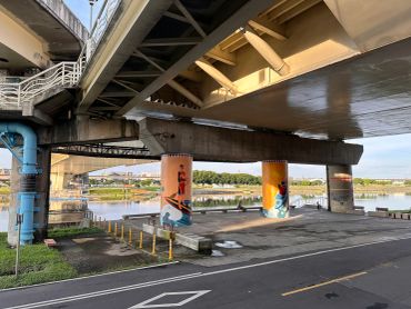 Under a bridge with painted pillars near a river.