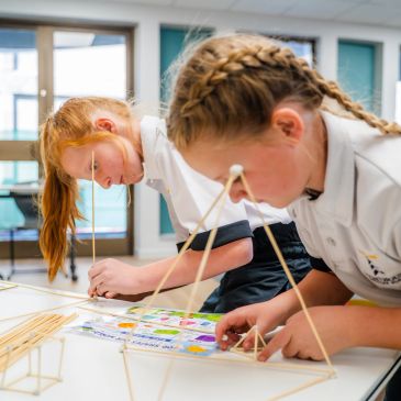 Two children building structures with sticks.