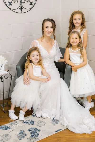 A bride posing for a picture with little bridesmaid