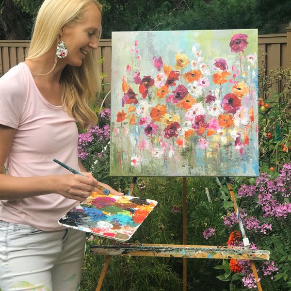 Woman painting colorful flowers outdoors.